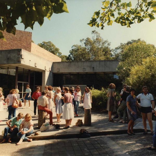 A group of students standing casually in front of a hall
