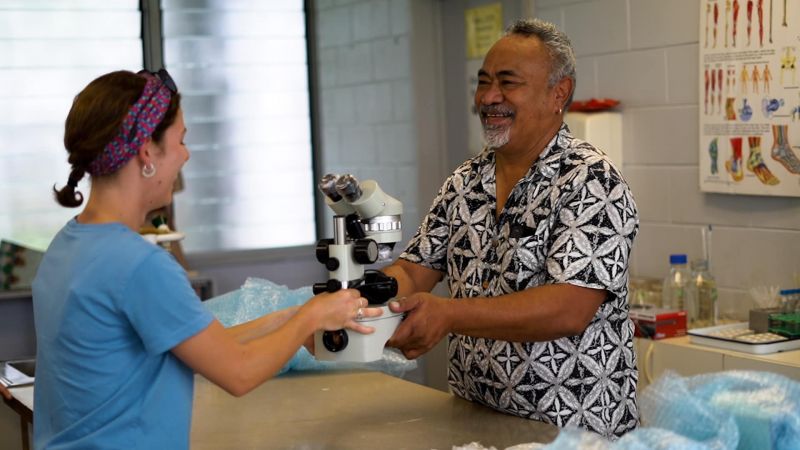 University of Newcastle student gifting a microscope to a leader at National University of Samoa 