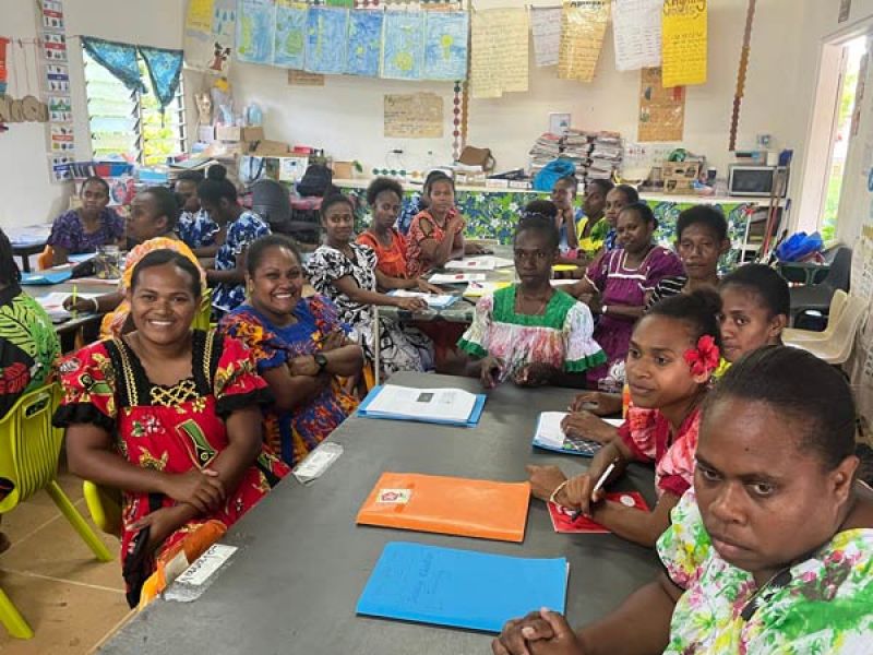 People in a classroom sitting around a desk
