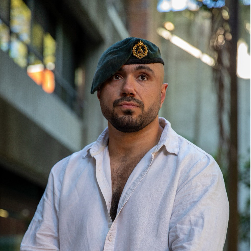 A man wearing a military beret, standing in front of a university building