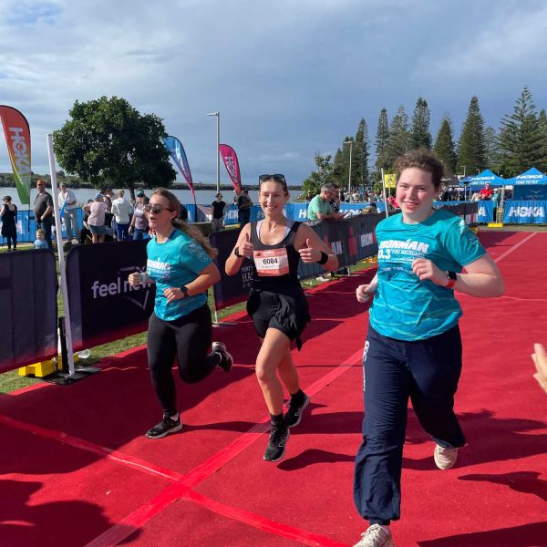 3 participants from the GHD team crossing the finish line of the 2024 IRONMAN challenge.