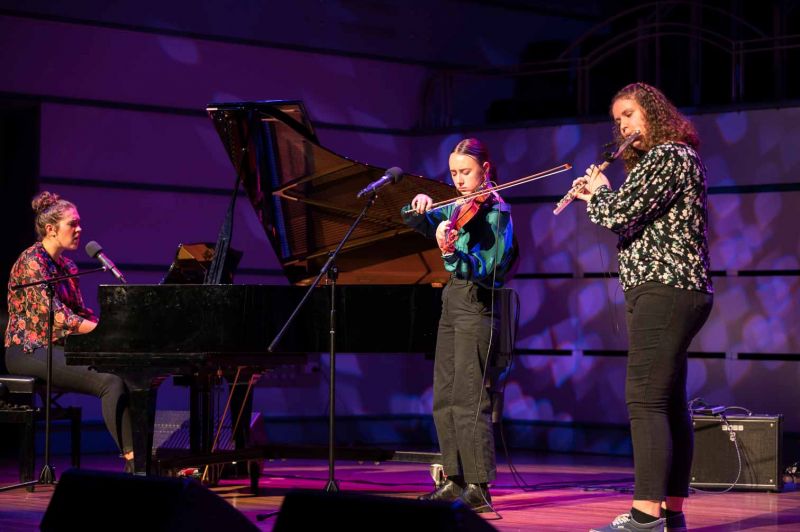 A pianist, violinist and a flautist performing on stage