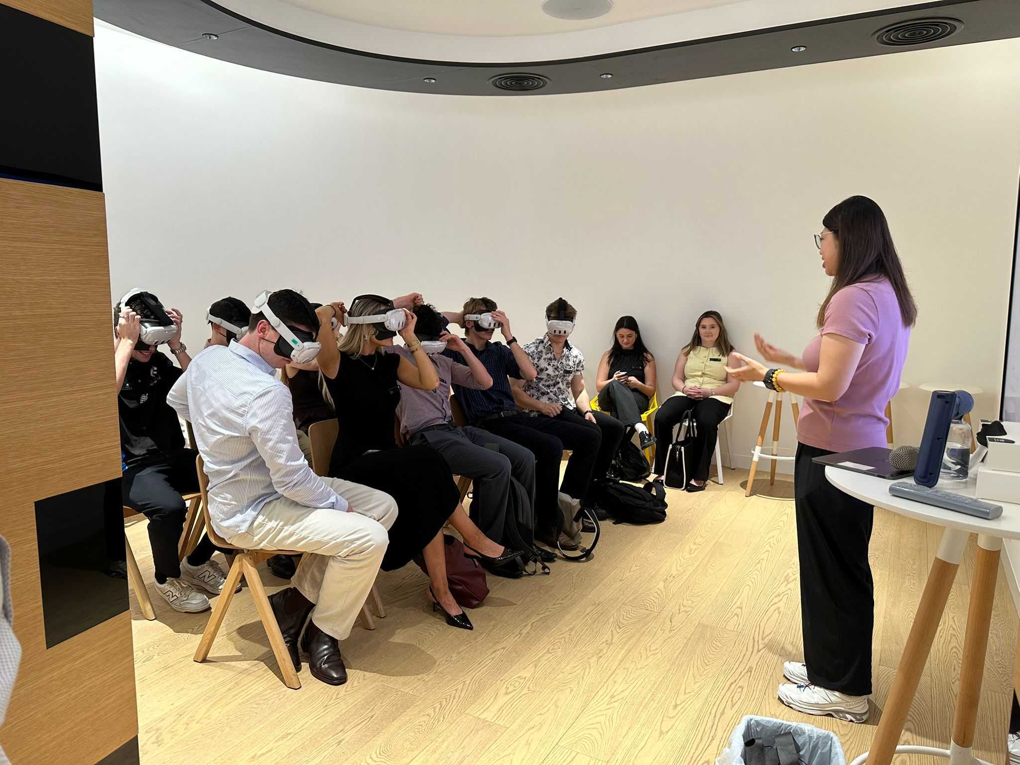 People sitting on chairs wearing virtual reality head sets.