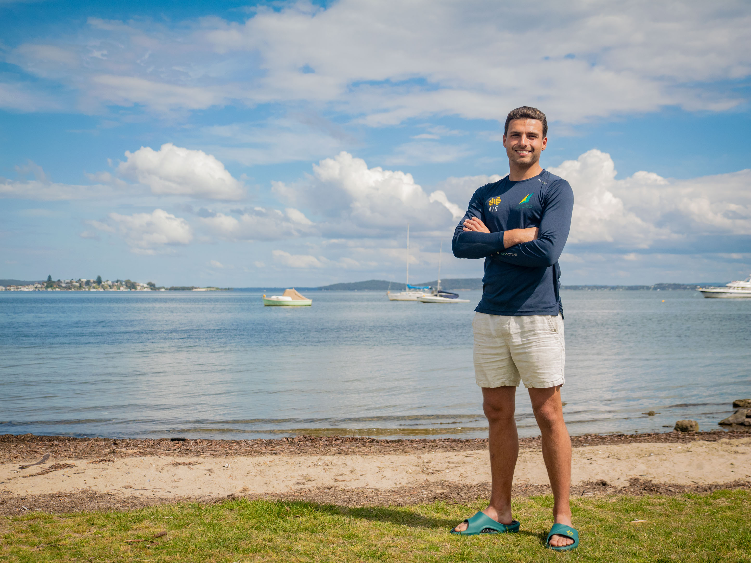 Brin Liddell won Sports Person of the Year Brin Liddell stands at the waters edge smiling with his arms crossed, the sky is bright blue with white clouds