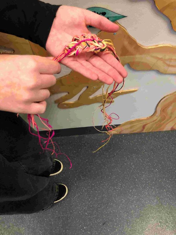 A sample of plaited weaving in bright colours in someone's hand
