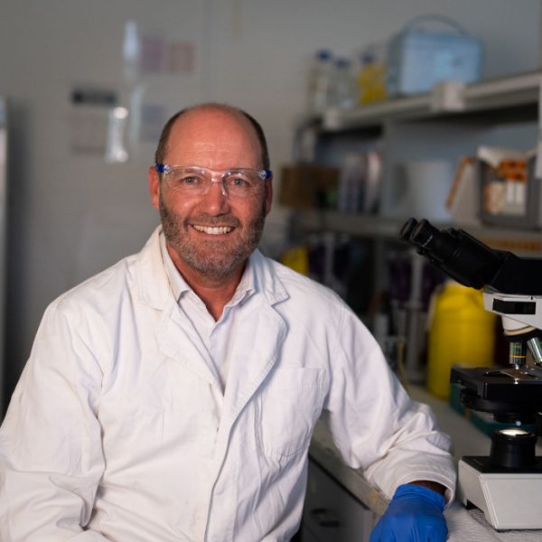 Professor Brett Nixon smiling to camera in a lab