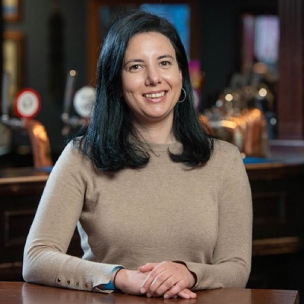 Woman with dark hair, sitting at a table and smiling for the camera