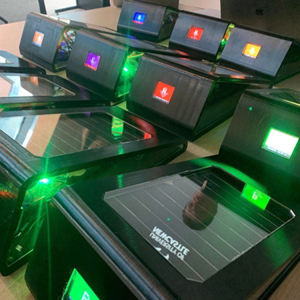A collection of small solar-powered electronic devices with illuminated coloured screens arranged together on a table.