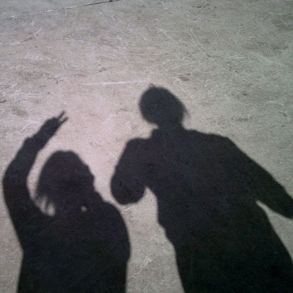 Photo shows the shadows of two people against concrete ground
