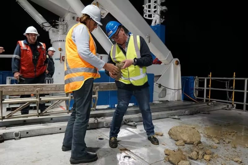 Researchers standing on boat deck with samples brought up from the sea floor. 