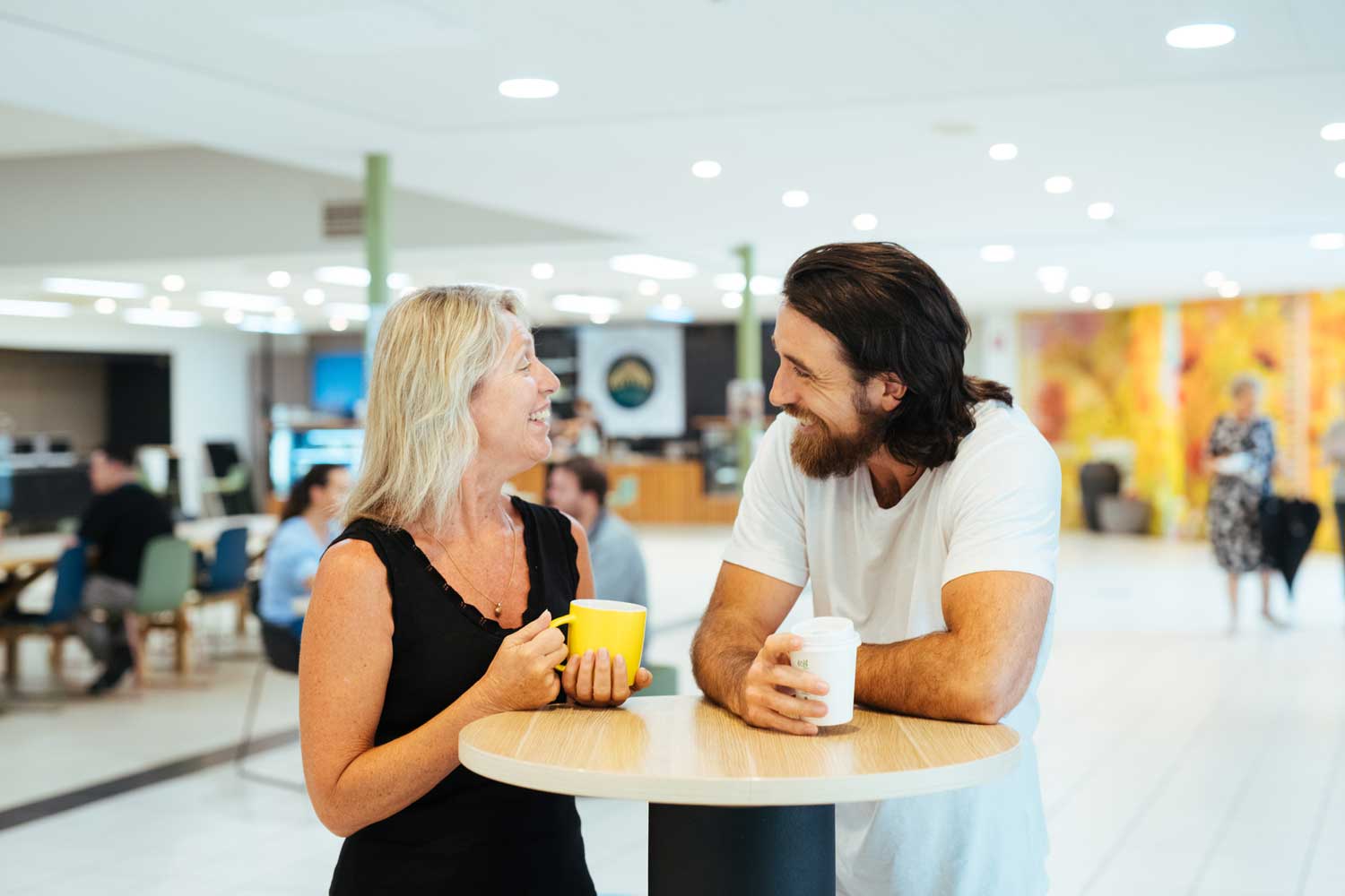 Two staff members talking and having coffee in a cafe.