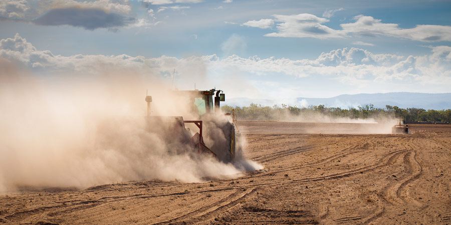 Tractors mixing up dirt on baron lands affected by drought.