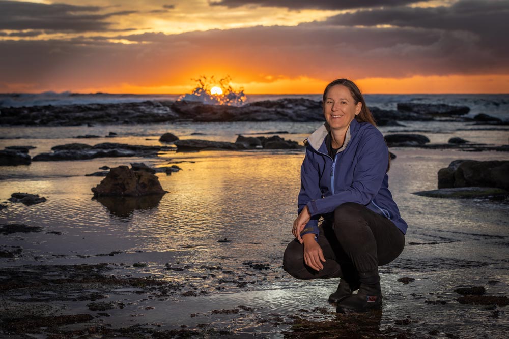 Dr Megan Huggett on a rock platform at sunrise.
