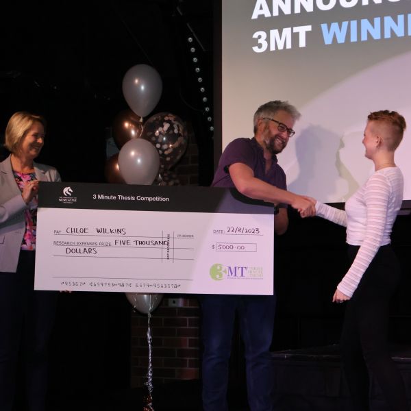3 Minute Thesis award winner Chloe Wilkins receives award on stage. Innovative research pitches win quick-fire University of Newcastle Three Minute Thesis and Visualise Your Thesis contest