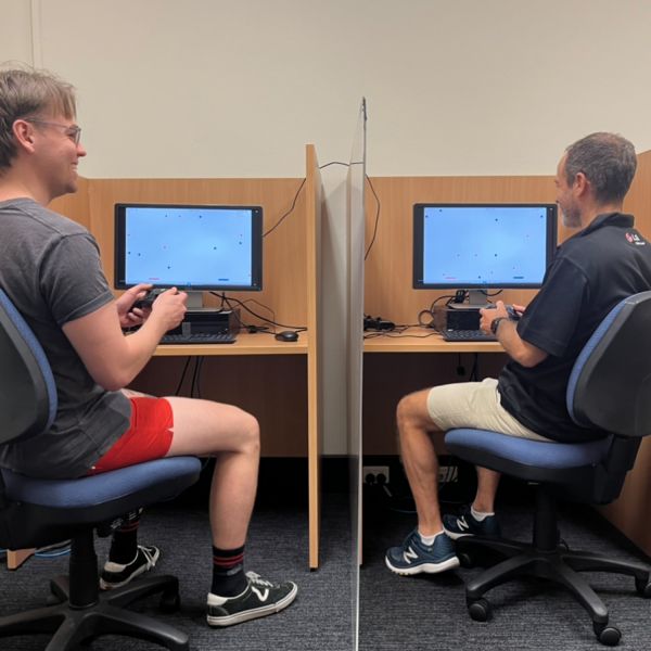 two researcher sitting at a computer screen each with a game displayed