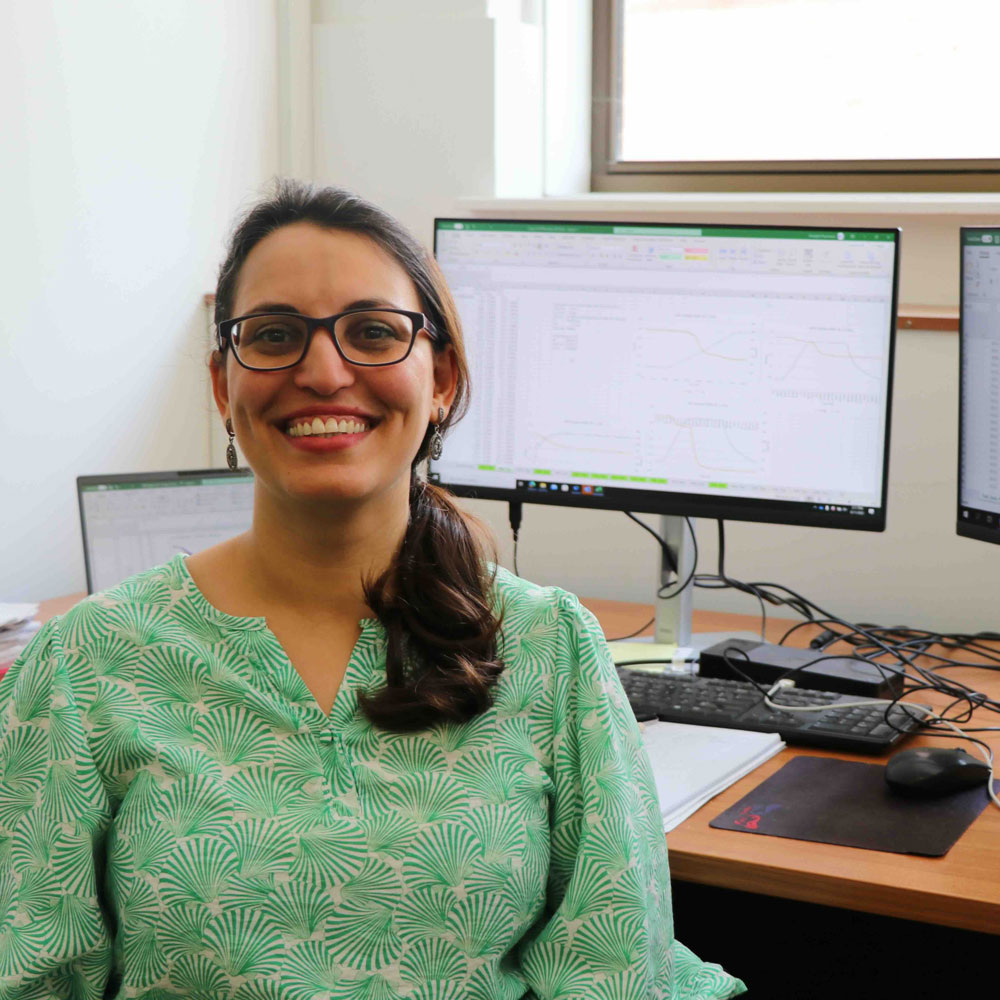 Sara Paymooni smiling at the camera in front of her computer