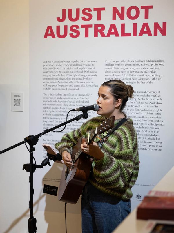 Young woman singing into microphone while playing guitar