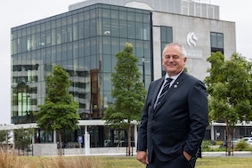 Image of the Vice-Chancellor Alex Zelinksy standing in front of the Q building in the city campus