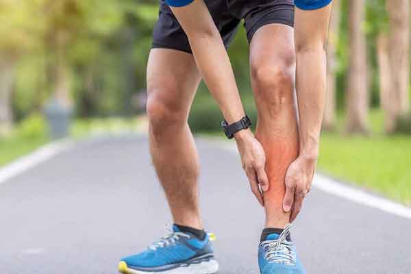 Podiatry A person grabbing their ankle in pain