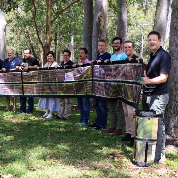 The COE group holding up a roll of printed solar outside on a sunny day. . University-made Printed Solar powers Coldplay concerts 