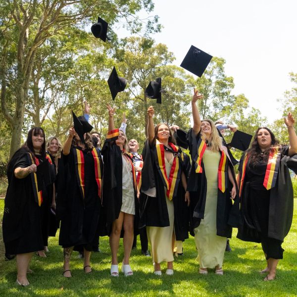Graduating Indigenous doctors throw their caps into the air. Education that empowers: University of Newcastle celebrates record graduation