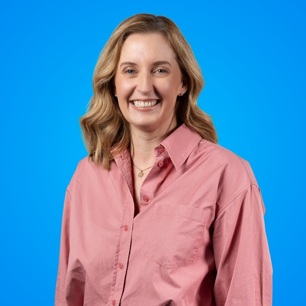 Woman smiling for the camera in front of a blue background