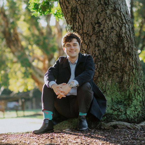 Brody McBain headshot A man sitting under a tree smiling