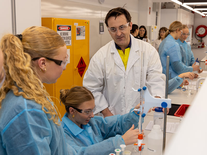Students use lab equipment, supervised by a staff member