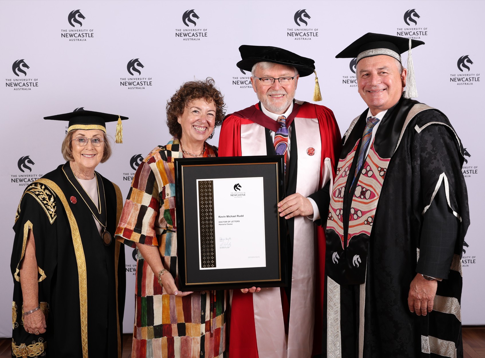 Chancellor Particia Forsythe, Therise Rein, Dr Rudd and Vice-Chancellor Prof Alex Zelinsky stand together smiling for the camera. Dr Rudd and his wife hold his certificate