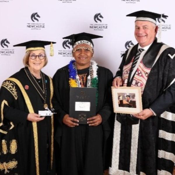 Two women and a man in graduation caps and gowns smile for the camera. Esther leads through education and culture.
