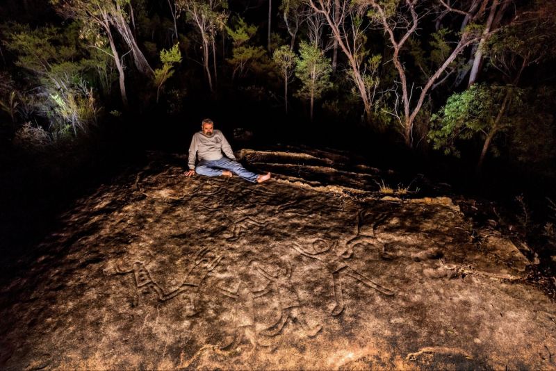 Uncle Warran Taggart seated on an engraved site in Yengo National Park 