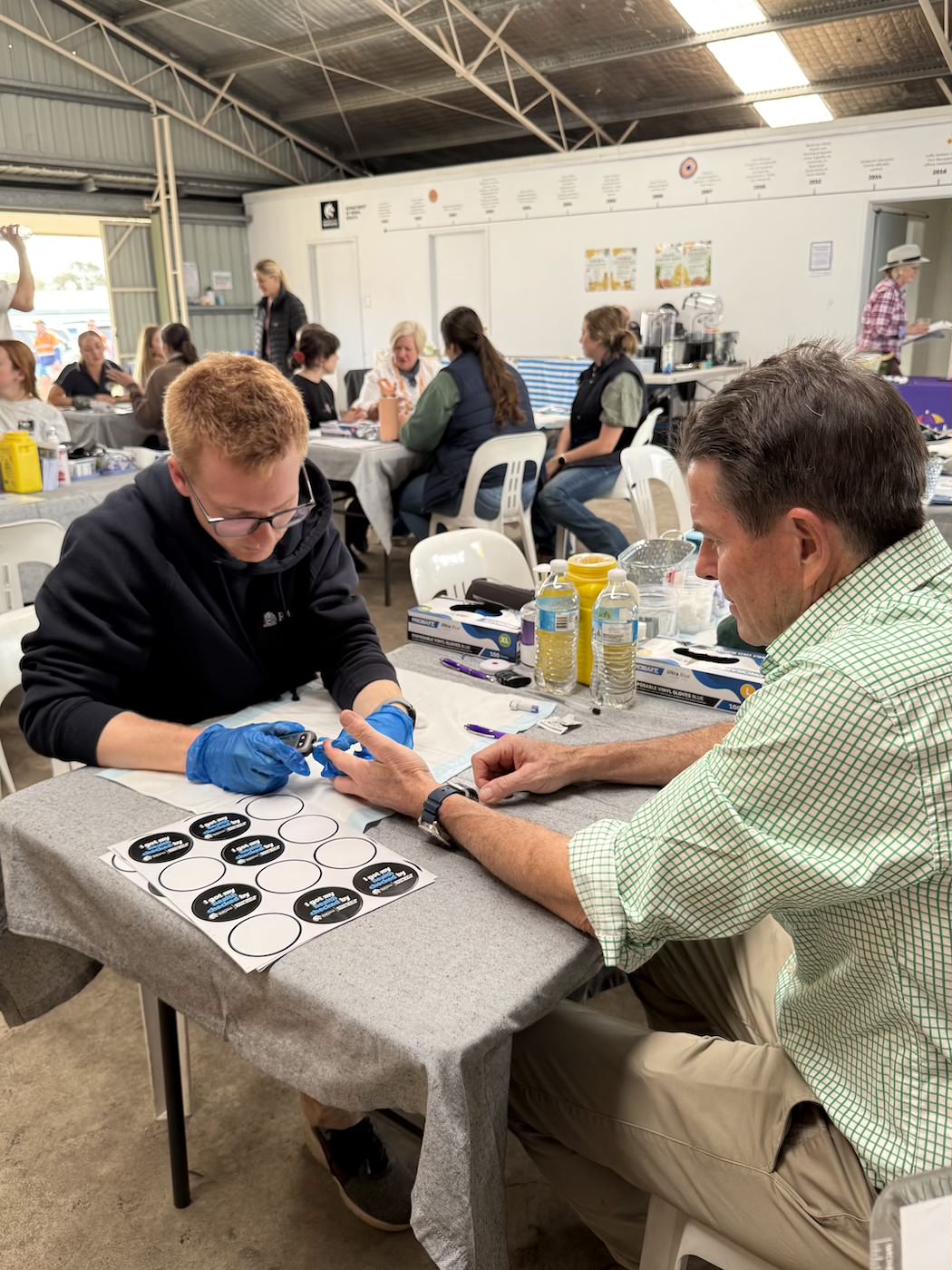 Photo of medicine student at AgQuip undertaking a health check with a community member