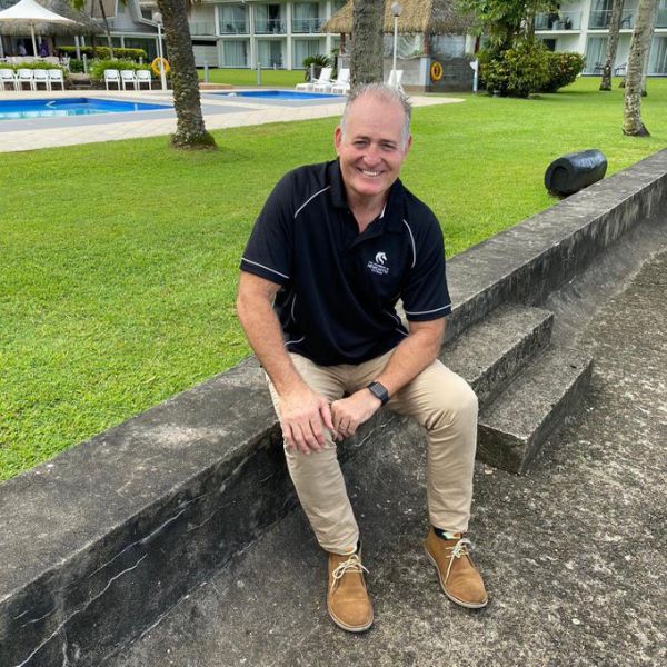 David Campese sitting on a concrete ledge at his hotel in Suva, Fiji. University of Newcastle Offers Campese Clinics for Rugby and Resilience