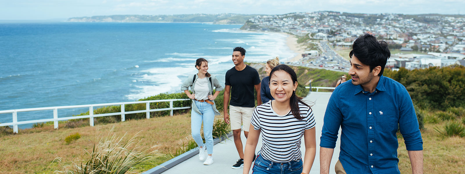 Students walking up a path with the beach in the background