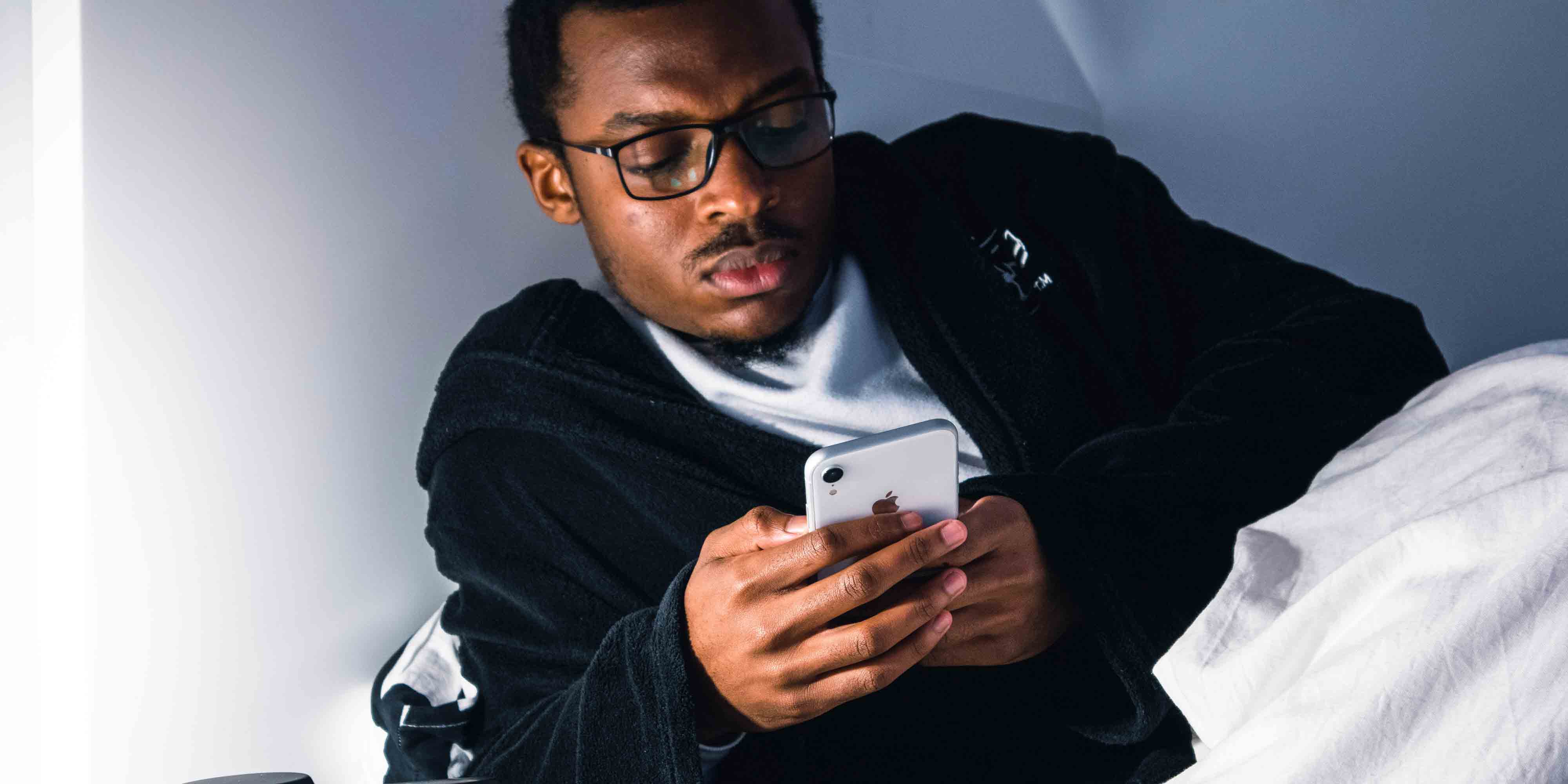 Man scrolling on phone in bed