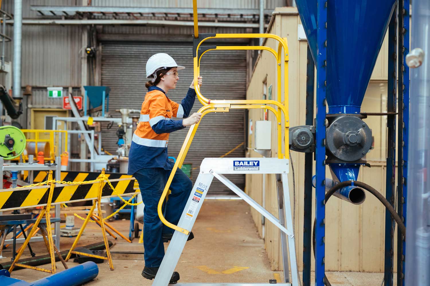 A woman in high vis clothing climbing a ladder safely. 