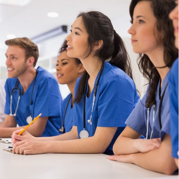 Diverse group of students in a learning environment wearing scrubs