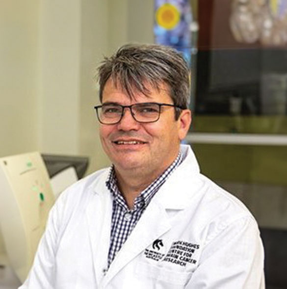 Man in glasses and lab coat smiling at camera
