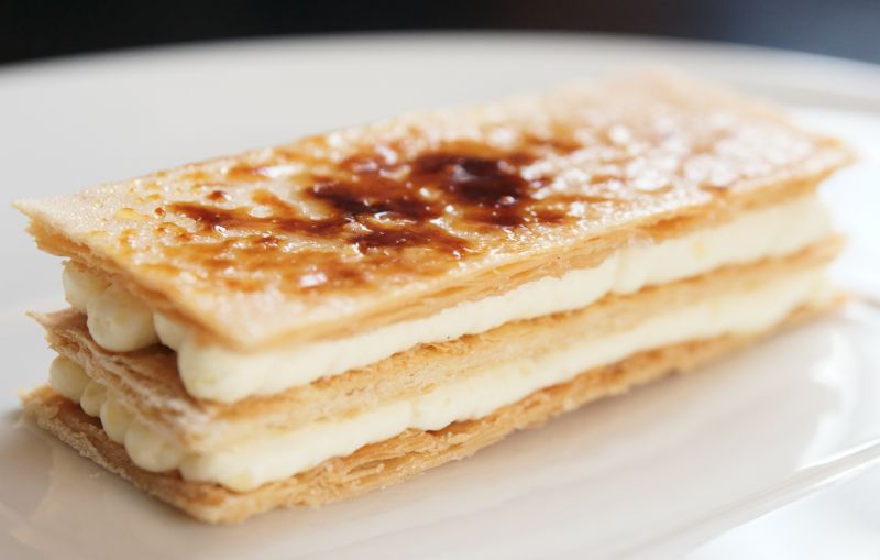 A mille-feuille, the French version of a vanilla slice, sitting on a white plate