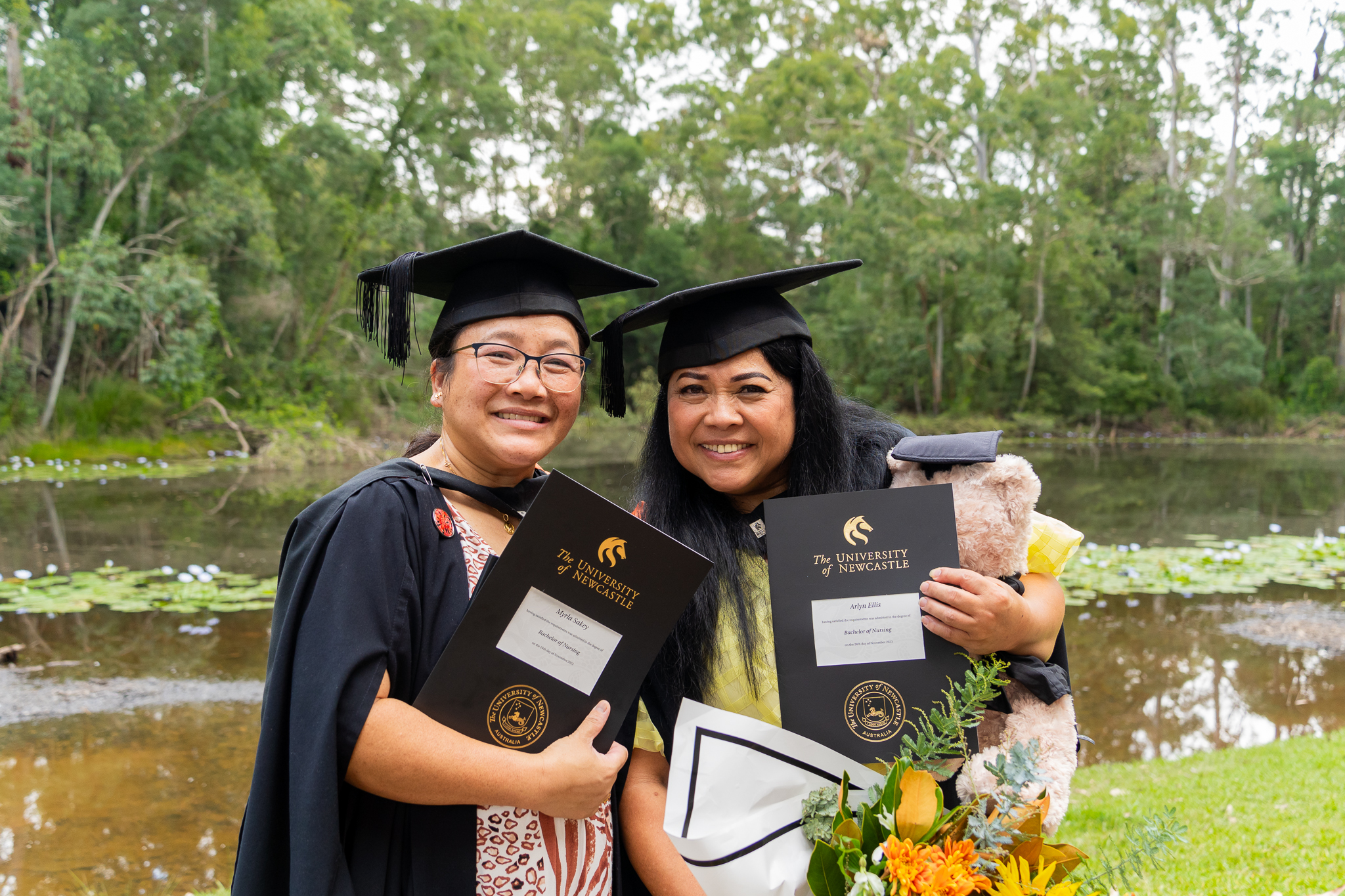 Graduates celebrate by the pond