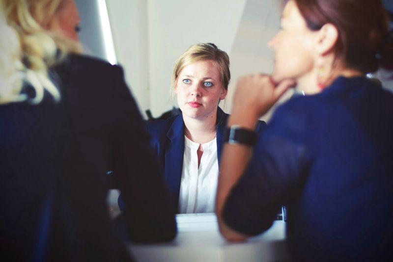 Three women in business attire sitting around a table