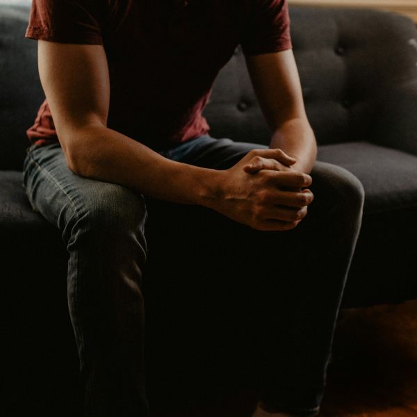 Man sitting on couch with hands clasped . Walk-and-Talk: University of Newcastle team taking men’s therapy outdoors