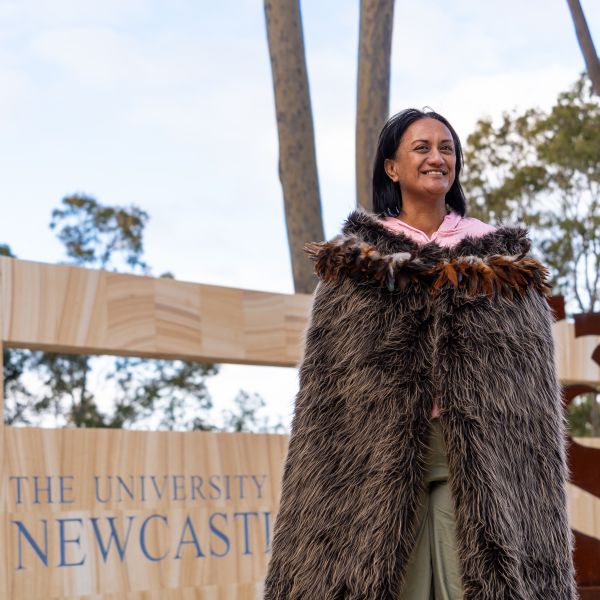 Ngaio Stobbs proudly wears a traditional Korowai cloak made of feathers and textile and smiles. Every student journey celebrated at University of Newcastle graduations.