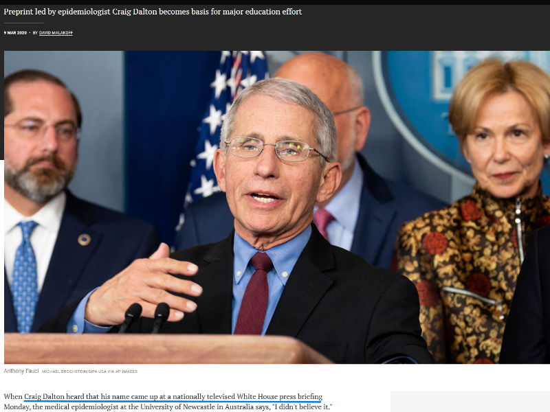 Man standing at a podium speaking to an audience with three people standing behind him