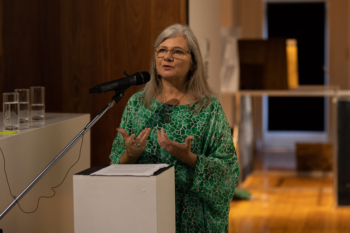 A woman standing and speaking at a plinth