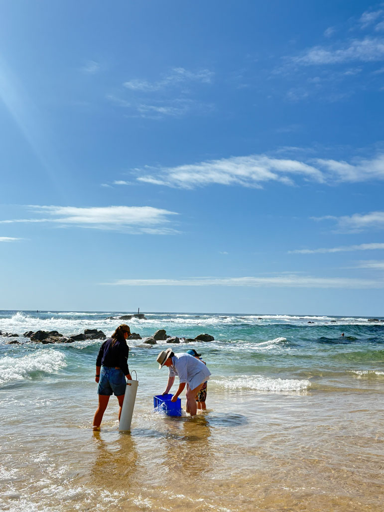 Community members hold their blue tub in the beach water
