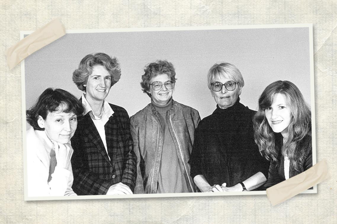 Five women stand in a row looking at the camera in a black and white photo