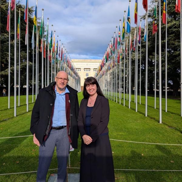 A man and woman standing in front of a row of flags