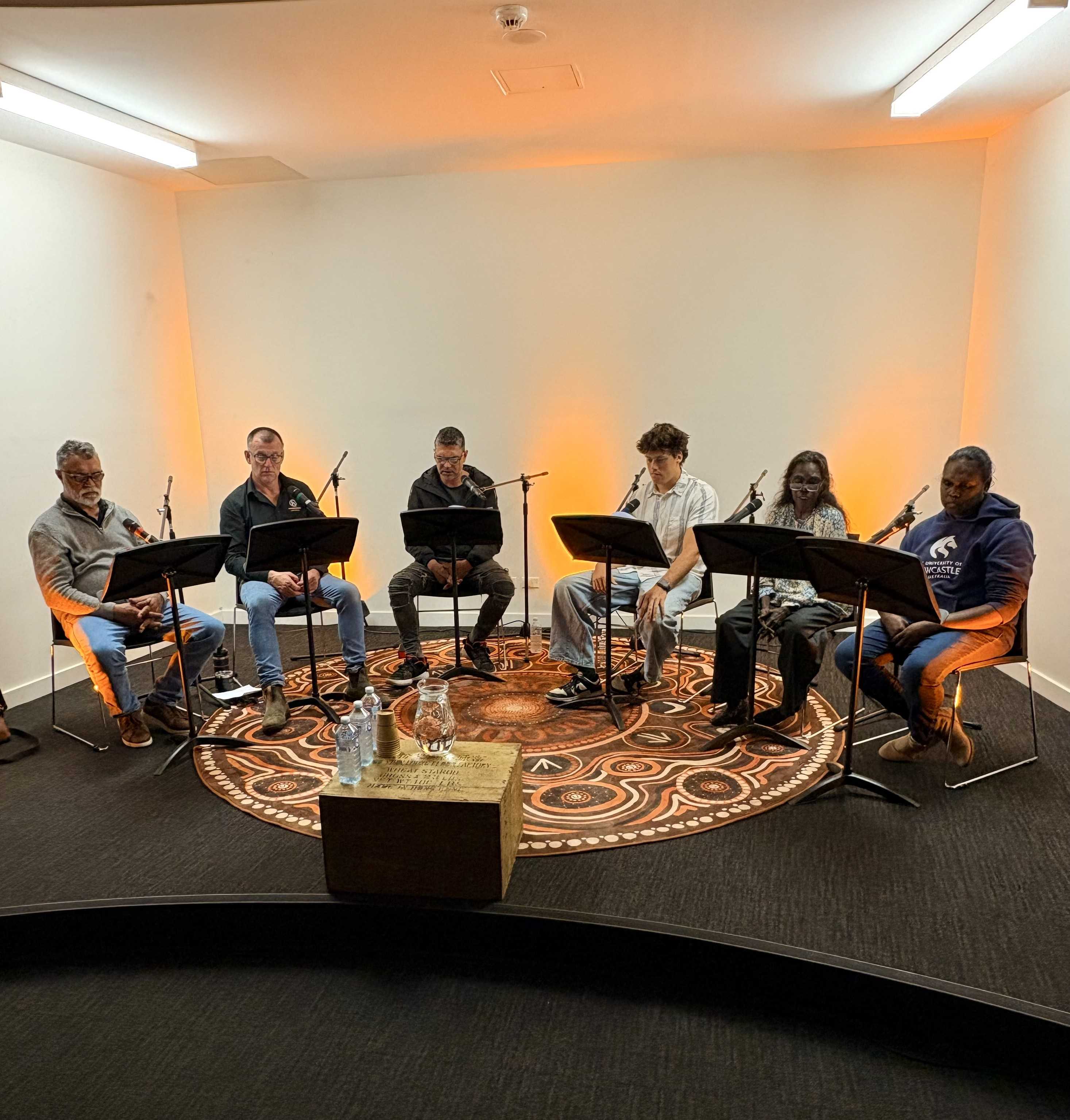 Script Reading speakers in a semi-circle reading the script on stage