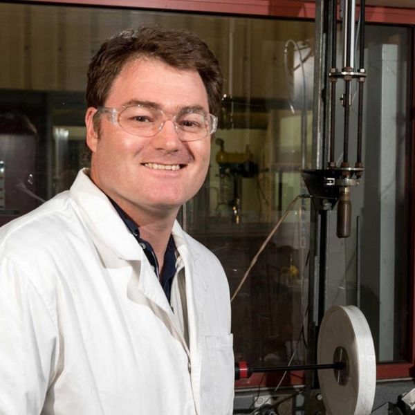 Image of a researcher in a lab wearing safety glasses and a lab coat